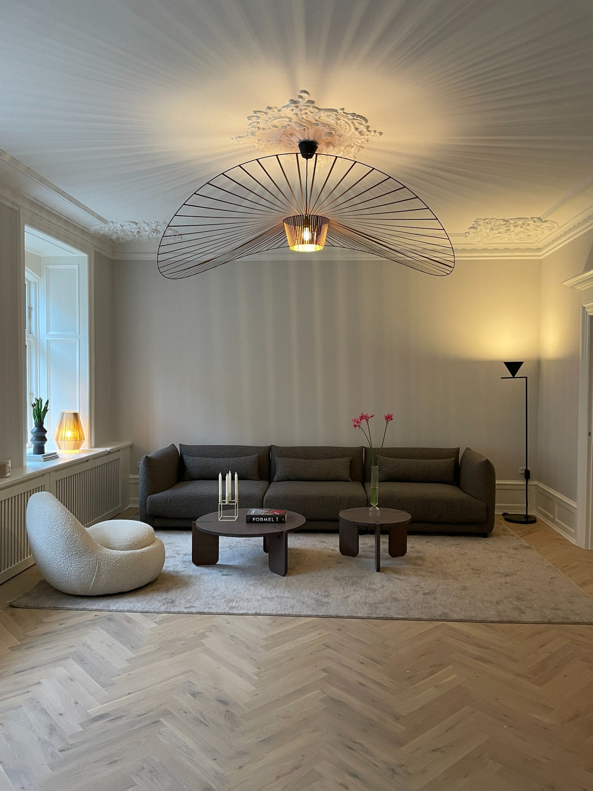 Indrettet stue med skulpturel loftslampe, sofa og loungestol